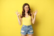 Smiling attractive woman showing okay signs and winking, assure you, praise and compliment smth good, recommending, standing over yellow background