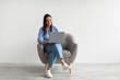 © Prostock-studio - Happy Caucasian lady sitting in armchair with modern laptop, studying remotely or having business meeting