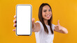 Woman showing white empty smartphone screen and thumbs up
