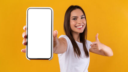 Wall Mural - woman showing white empty smartphone screen and thumbs up