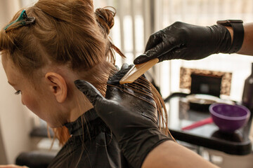 .Close-up of female hands holding the hair rows in professional hairstyles salon. The hairdresser paints or makes keratin to a girl in a professional salon