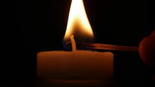 Lighting A Candle With A Fired Match. Man Illuminating With A Candle A Dark Room In Time Of An Accidental Power Failure.