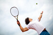 © NDABCREATIVITY - Young handsome tennis player with racket and ball prepares to serve at beginning of game or match.