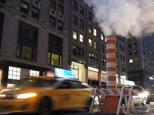 Long Exposure Image Of A Cab Passing By A Steam Stack In New York.