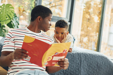 In domestic room. African american father with his young son at home