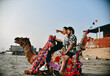 young happy couple side pose sitting on camel at beach indian pakistani model