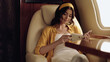 © LIGHTFIELD STUDIOS - Young smiling woman reading book in private jet.