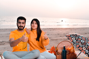 Wall Mural - casual happy young happy couple thumb up on beach indian pakistani model on beach indian pakistani model