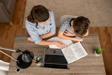 Wall Mural - education, family and school concept - mother and son with book , notebook and laptop computer doing homework together at home