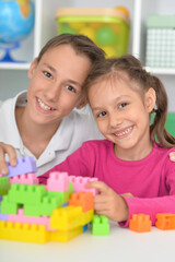 Wall Mural - Brother and sister playing with colorful plastic blocks together