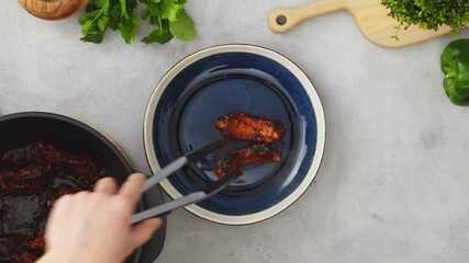 Wall Mural - Crop person putting fried ribs on plate