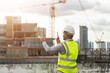 © Chanakon - Asian engineer handsome man or architect use radio communication with white safety helmet in city construction site . Standing on rooftop building construction at capital.