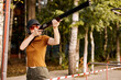Side view gun point of rifle machine gun. Firearm shooting and tactical weapons training. Outdoor shooting range. Focused lady in eyeglasses holding gun in hands, shooting, training alone