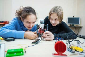 two teenager girls at robotics school makes robot managed from the constructor, children learn robot