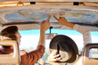 Summer travel concept. young friends or couple looking at map above to plan a camper van trip pointing finger at map. vacation, holidays, adventure, journey, trip, travel concept. rear view