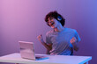 gamer cyberspace playing with headphones in front of a laptop violet background