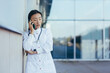 Sad and frustrated female doctor talking on the phone near the clinic, Asian depressed and tired after work