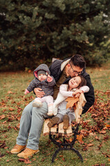 Wall Mural - A single father with two daughters sitting on a bench in the park
