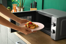 Woman Heating Food In Microwave Oven