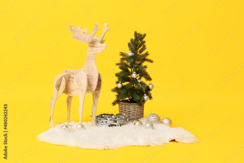 Wooden reindeer with Christmas tree on yellow background