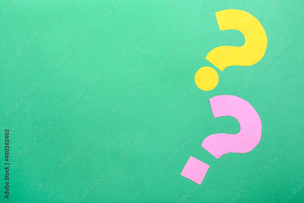 Question marks made of paper on green background