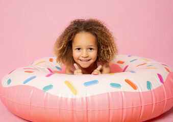 Poster - Portrait of happy little girl with inflatable rubber circle having fun isolated on pink background