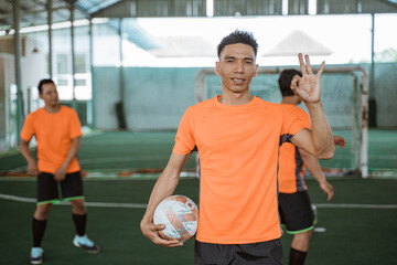 Wall Mural - male futsal players standing poses with an ok hand gesture