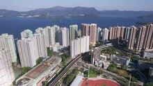 Football Field And Running Track Between The High Populated Skyscrapers Of Vista Paradiso While A Train Is Moving Over The Railway Track In Hongkong. Wide Drone Dolley Lifting Shot