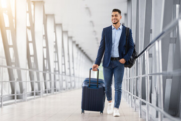 Ready For Trip. Handsome Arab Guy Walking With Suitcase At Airport Terminal