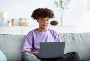 Canvas Print - Home schooling. Black teenage guy having online class, using laptop, talking to fellow students or teacher