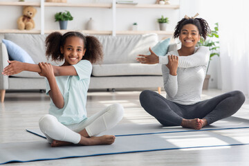 Wall Mural - Happy black mother and daughter stretching at home