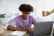 © Prostock-studio - Serious black teen guy writing in notebook during webinar or lesson on laptop at home