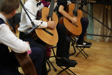 Wall Mural - A group of young guitarists boys musicians playing guitar performing sitting on the stage of a school concert