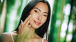 © Gorodenkoff - Portrait of Beautiful Asian Woman Gently Applying Face Cream. Young Adult Female Makes Her Skin Soft, Smooth Using Scientifically Advanced Natural Cosmetics Skincare Product. Green Forest Background