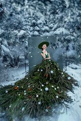 Beautiful woman with christmas tree dress in winter forest.