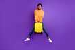 Full size photo of young black man happy positive smile jump hold suitcase travel vacation isolated over violet color background