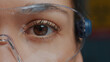 © DC Studio - Woman with protective glasses showing one eye in front of camera, brown eye blinking and focusing sight. Person wearing safety goggles, with half of face. Genetic anatomy. Close up