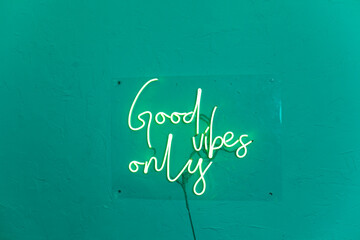 neon words on the turquiose wall. good vibes only neon sign at the bar, cafe or at home.