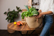© Dina - woman in white shirt and jeans holding an eco jute reusable bag with bunch of green basil and lettuce. Grocery shopping for vegetables - healthy lifestyle