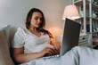 © oneinchpunch - Woman working on the laptop before going to sleep