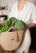 © Dina - Unrecognizable woman in white shirt taking out broccoli and vegetables out of eco reusable bag after grocery shopping for healthy food.