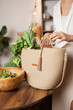 © Dina - Unrecognizable woman in white shirt taking out green vegetables out of eco reusable bag after grocery shopping for healthy food.