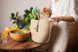© Dina - Unrecognizable woman in white shirt taking out green vegetables out of eco reusable bag after grocery shopping for healthy food.