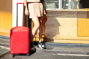  Female traveler walking with red suitcase in the city