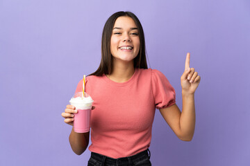 Wall Mural - Teenager girl holding a strawberry milkshake pointing up a great idea