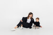 © LIGHTFIELD STUDIOS - stylish and cheerful woman sitting near toddler son on grey.