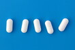 Five white oblong tablets lie on a blue background.