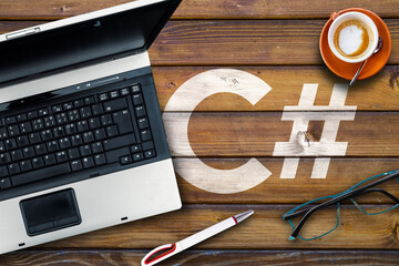 C sharp programming language. C# and laptop, glasses and coffee on wooden table