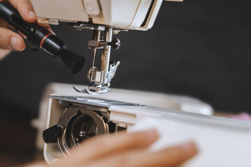 A young woman cleaning a sewing machine.