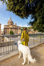 Woman With Her Dog Enjoying View On The Roman Forum In The Centre Of Rome. Concept Of Italian Lifestyle And Traveling Italy. Woman Wearing Coat And Shawl In Hair With Italian Shepherd Dog